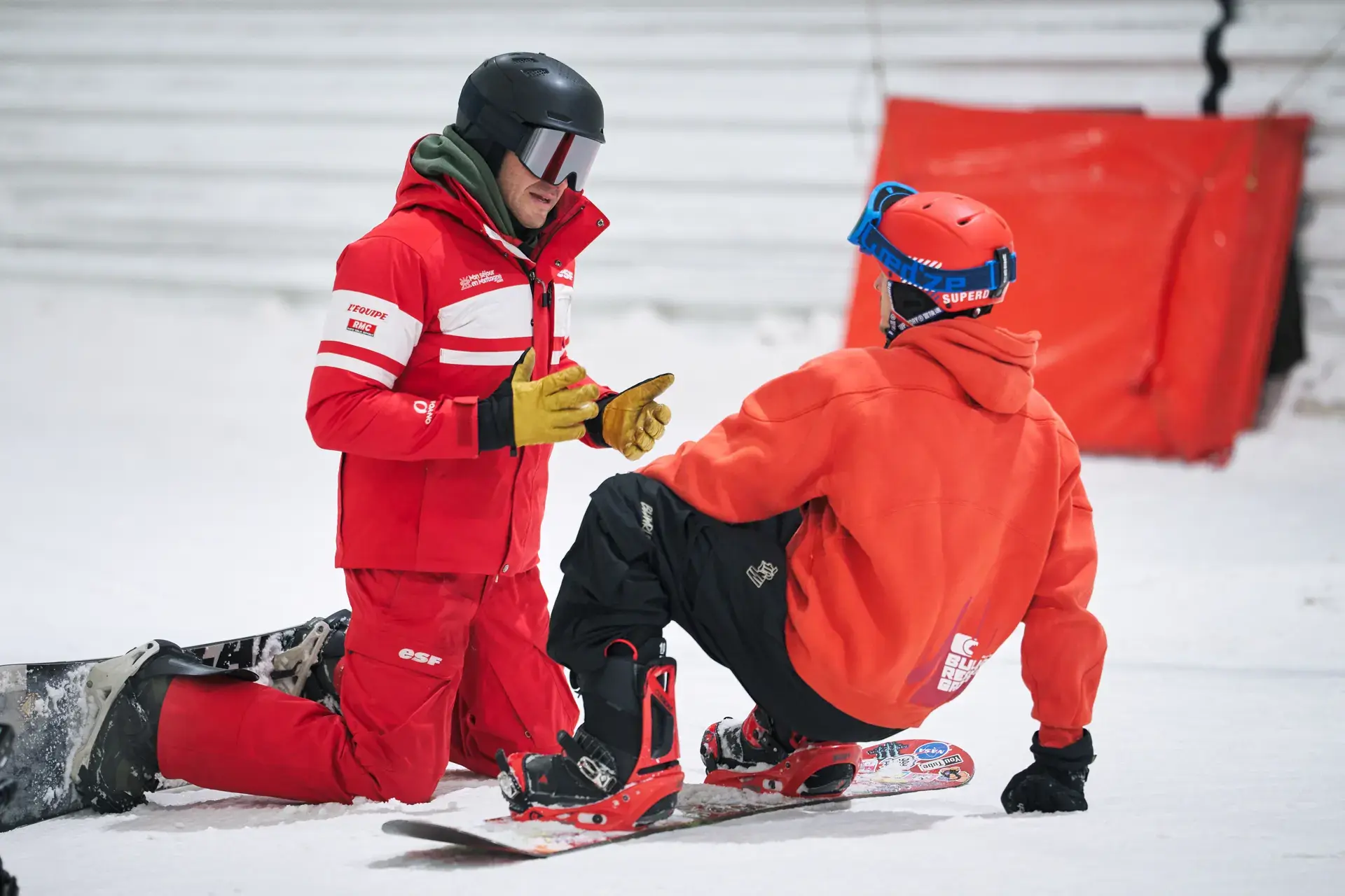 Moniteur de l’ESF Amnéville aidant un élève en snowboard sur la piste indoor
